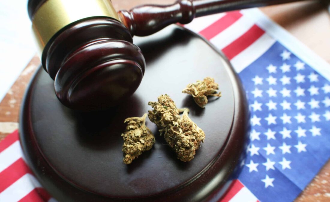 Close up of gavel and marijuana buds sitting on an American flag to signify medical marijuana legalization.